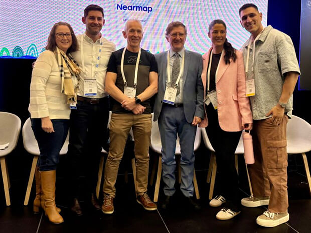 A group of people in a conference setting, smiling to camera.