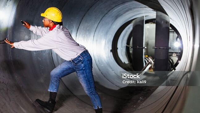 A person with a hardhat on, standing in a tunnel