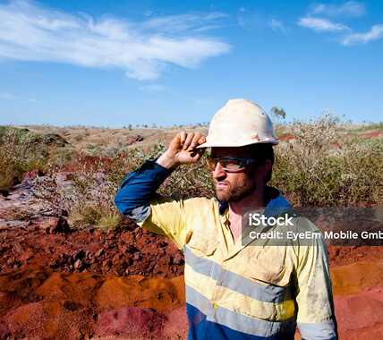 A mine worker holding on to the hardhat on his head
