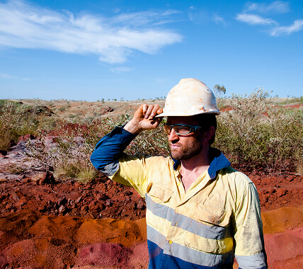 A mine worker holding on to the hardhat on his head