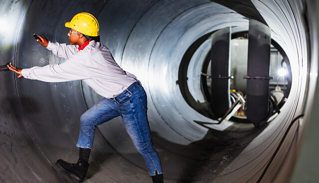 A person with a hardhat on, standing in a tunnel