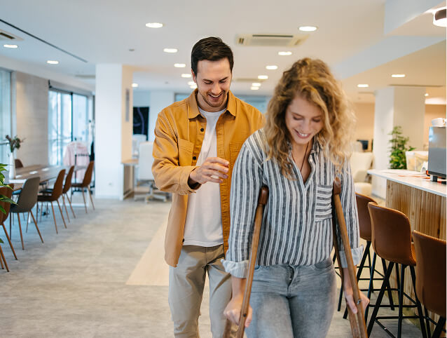 A man assisting a woman on crutches