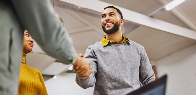 A smiling man receiving a handshake