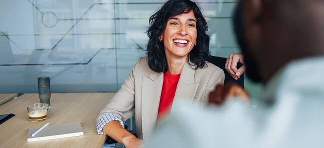 A woman in a corporate setting, smiling to a person who is off-camera